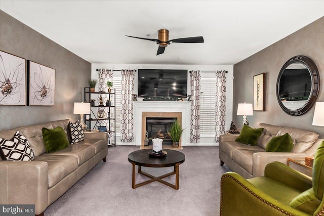carpeted living area with a fireplace with flush hearth and ceiling fan