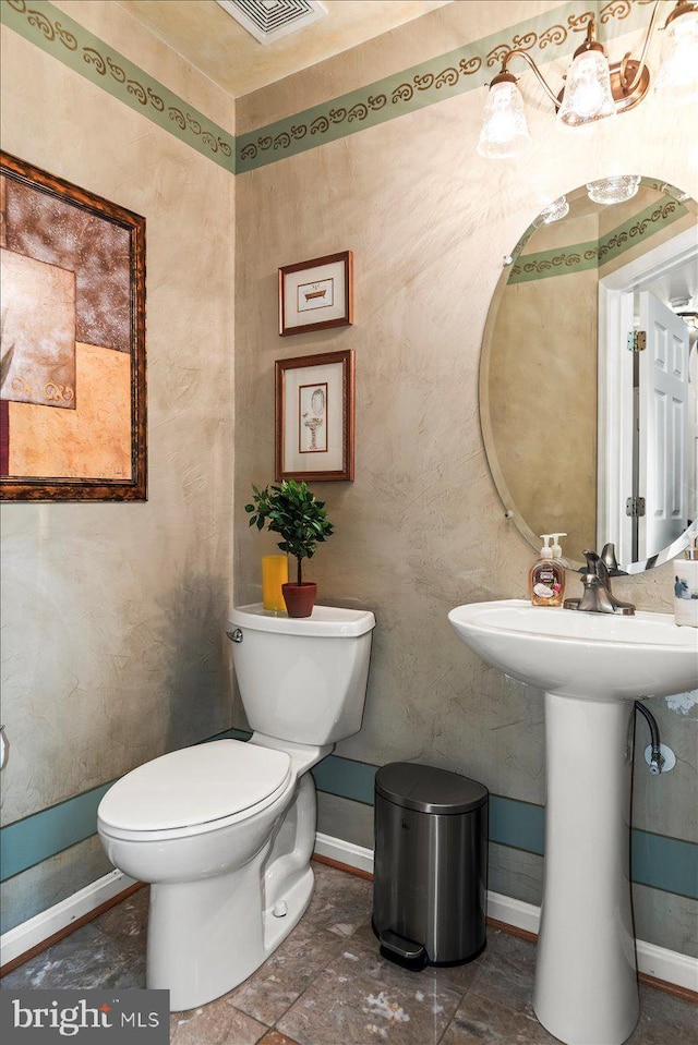 half bathroom featuring baseboards, a sink, visible vents, and toilet