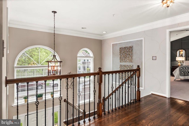 corridor featuring baseboards, ornamental molding, wood finished floors, and an upstairs landing