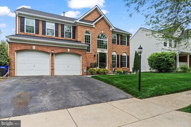 view of front facade featuring brick siding, a garage, aphalt driveway, and a front yard