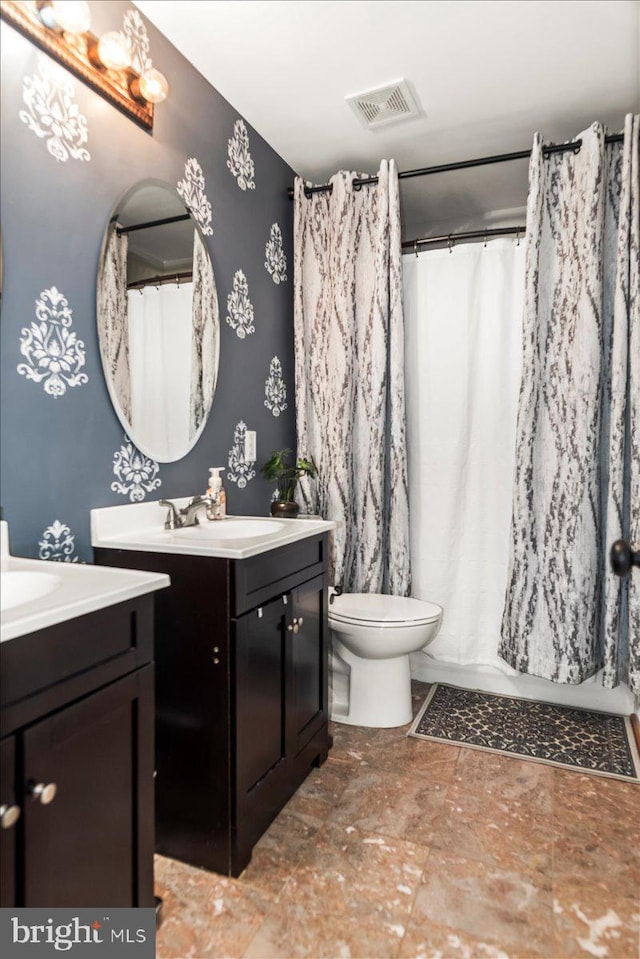bathroom featuring visible vents, toilet, a shower with shower curtain, two vanities, and a sink