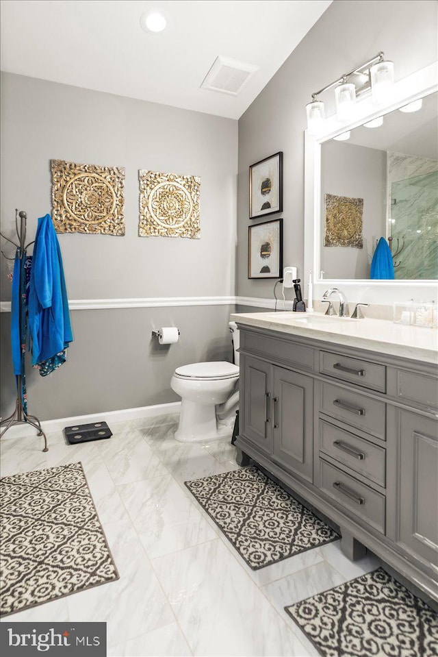 bathroom with vanity, toilet, marble finish floor, baseboards, and visible vents