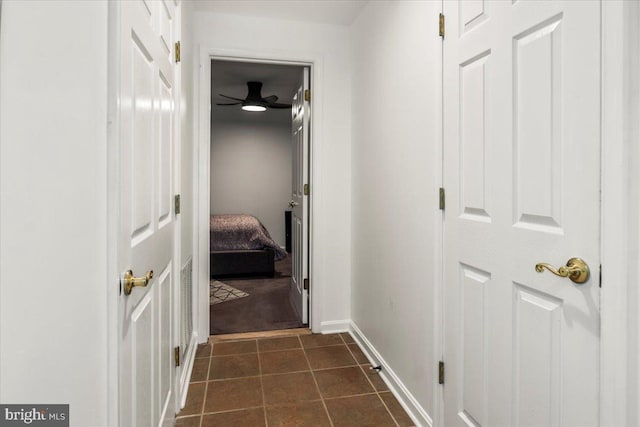 hallway with baseboards and dark tile patterned floors