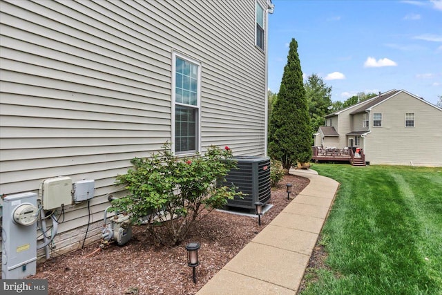 view of side of property with a lawn, central AC unit, and a deck