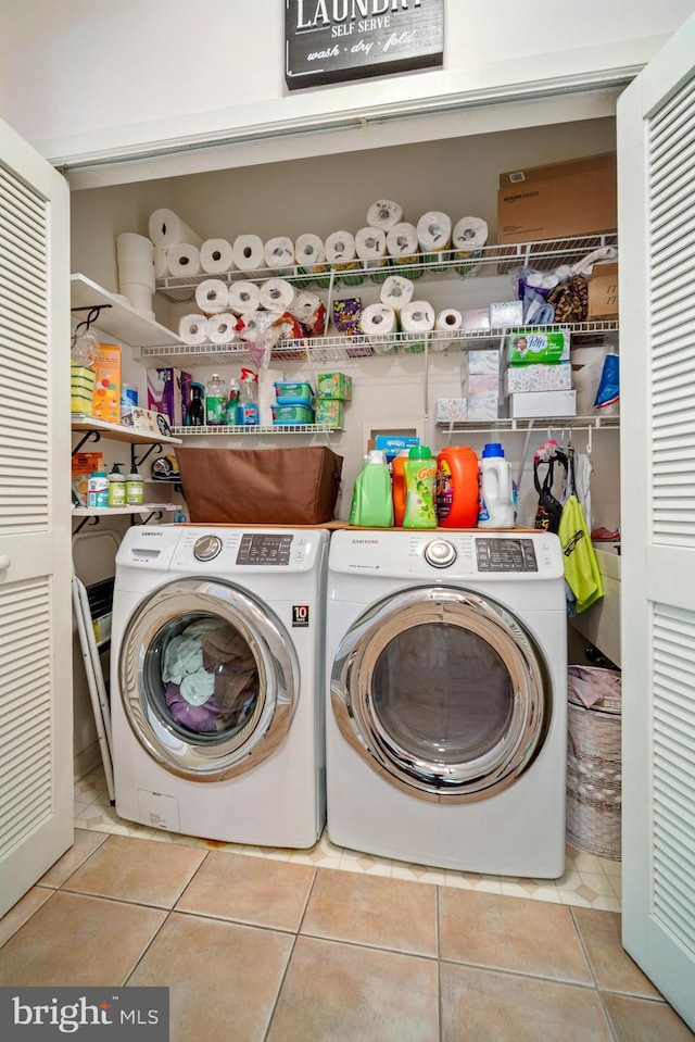 clothes washing area with laundry area, washer and clothes dryer, and tile patterned flooring