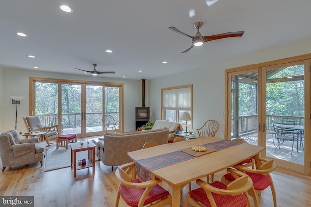 dining area featuring a ceiling fan, recessed lighting, light wood-style flooring, and a wood stove