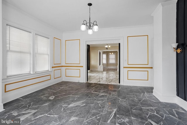 unfurnished dining area featuring crown molding, a notable chandelier, baseboards, marble finish floor, and a decorative wall