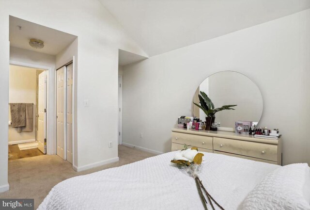 bedroom with connected bathroom, baseboards, vaulted ceiling, and light carpet