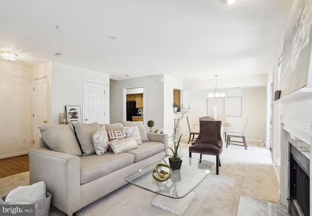 living room featuring an inviting chandelier, a fireplace with flush hearth, and baseboards