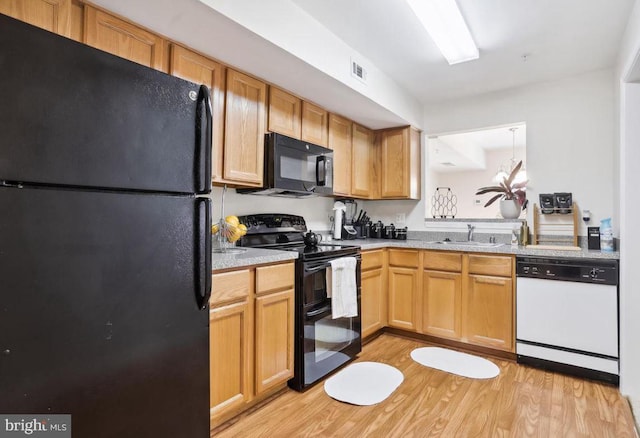 kitchen featuring visible vents, light wood-type flooring, light countertops, a sink, and black appliances