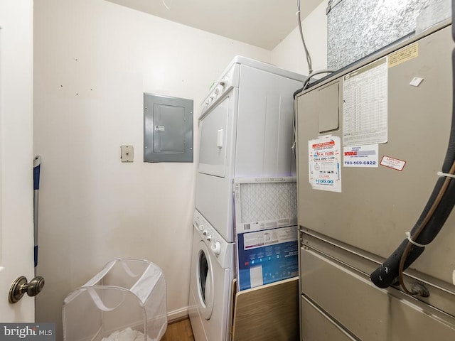 washroom with laundry area, stacked washer and dryer, heating unit, and electric panel