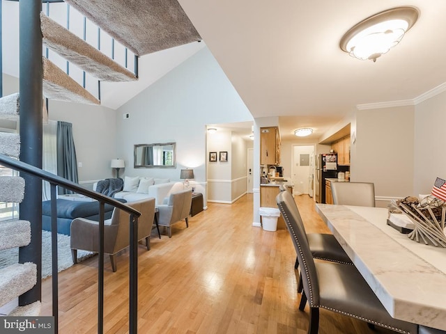 dining space featuring crown molding, light wood-type flooring, stairway, baseboards, and a high ceiling
