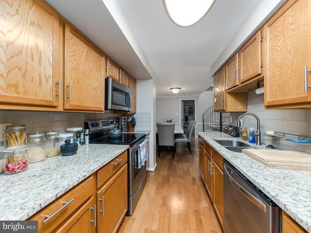 kitchen featuring decorative backsplash, a sink, appliances with stainless steel finishes, and light wood finished floors