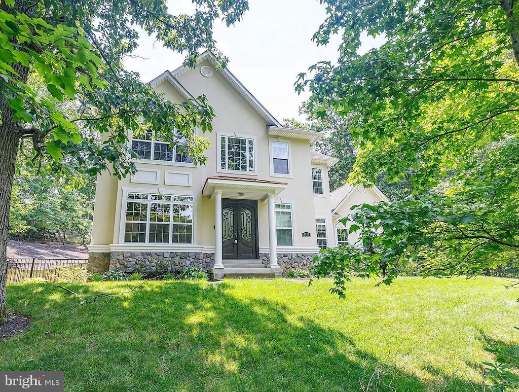 view of front of house featuring stone siding, french doors, a front yard, and stucco siding