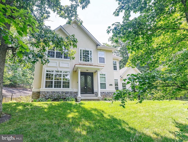 view of front of house featuring stone siding, french doors, a front yard, and stucco siding