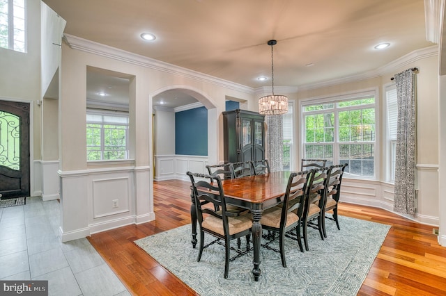 7140 Barry Rd, Alexandria, VA 22315 - dining space with arched walkways, a chandelier, a decorative wall, plenty of natural light, and light wood-style flooring