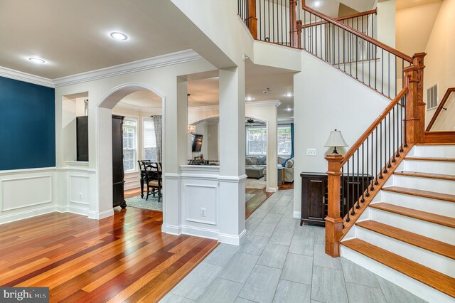 7140 Barry Rd, Alexandria, VA 22315 - entryway featuring arched walkways, plenty of natural light, crown molding, light wood-style floors, and stairs