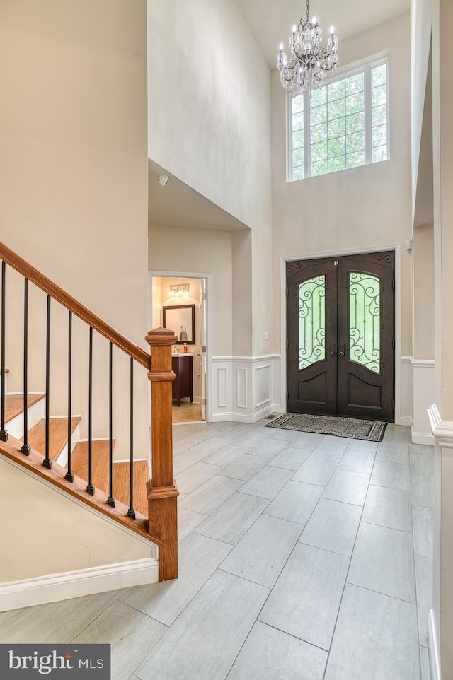 7140 Barry Rd, Alexandria, VA 22315 - foyer entrance featuring a high ceiling, a chandelier, stairway, french doors, and a decorative wall