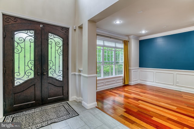 7140 Barry Rd, Alexandria, VA 22315 - entrance foyer featuring light wood-style floors, french doors, ornamental molding, wainscoting, and a decorative wall