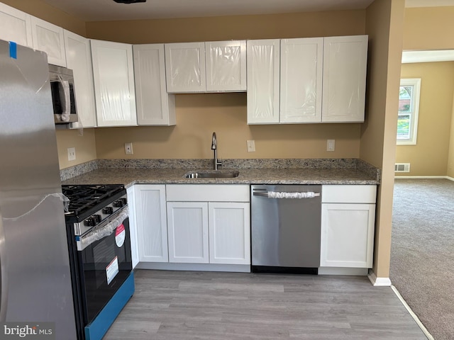 9016 Samoset Rd, Randallstown, MD 21133 - kitchen with visible vents, white cabinetry, a sink, light wood finished floors, and appliances with stainless steel finishes