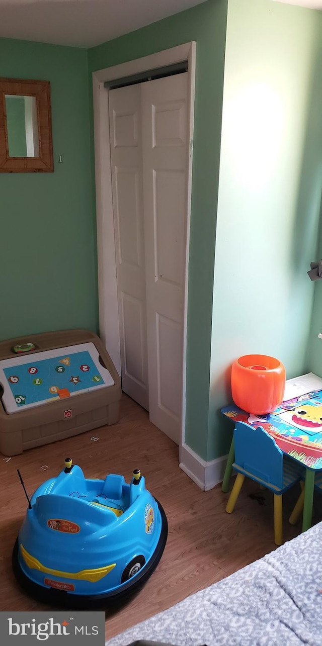 bedroom featuring baseboards, wood finished floors, and a closet