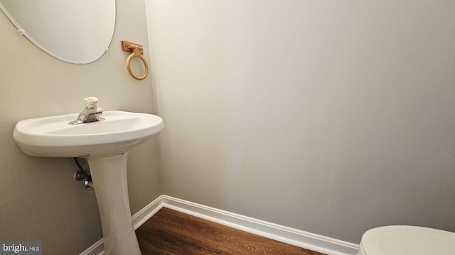 half bathroom featuring toilet, baseboards, and wood finished floors