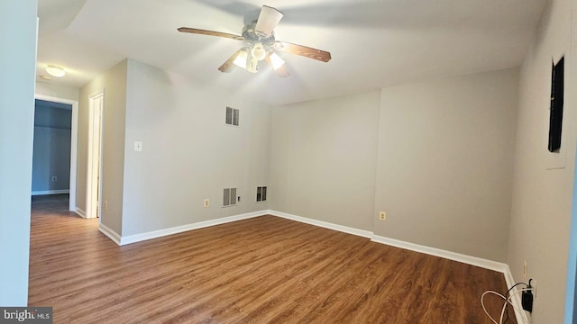 unfurnished room featuring baseboards, wood finished floors, and visible vents