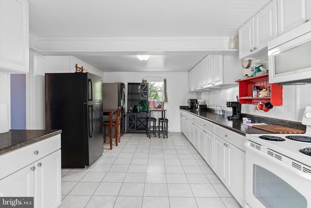 kitchen with dark countertops, white cabinetry, light tile patterned floors, and white appliances