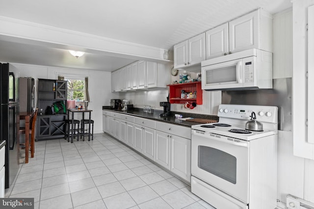 kitchen with white appliances, light tile patterned flooring, dark countertops, and white cabinetry