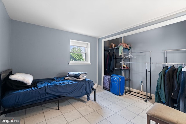 bedroom with tile patterned floors, baseboards, and a closet