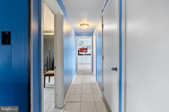 corridor featuring baseboards and light tile patterned flooring