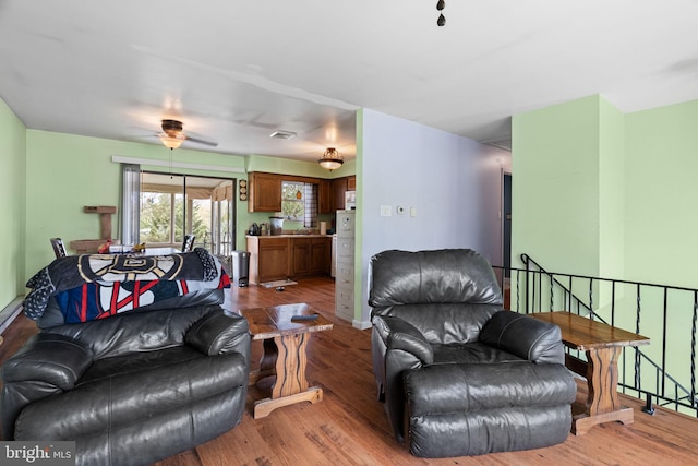 living area featuring baseboards, a ceiling fan, and wood finished floors