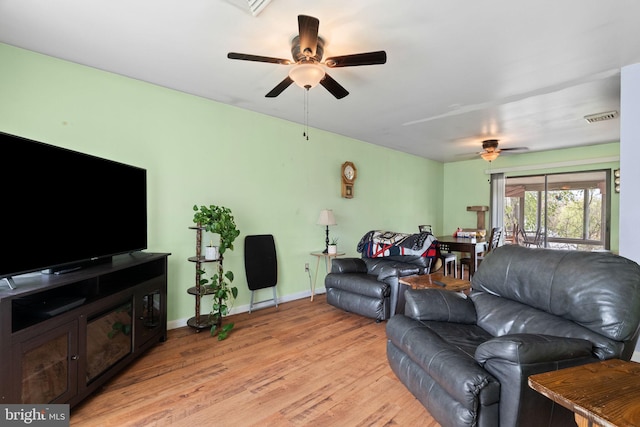 living room featuring baseboards, ceiling fan, visible vents, and light wood-style flooring