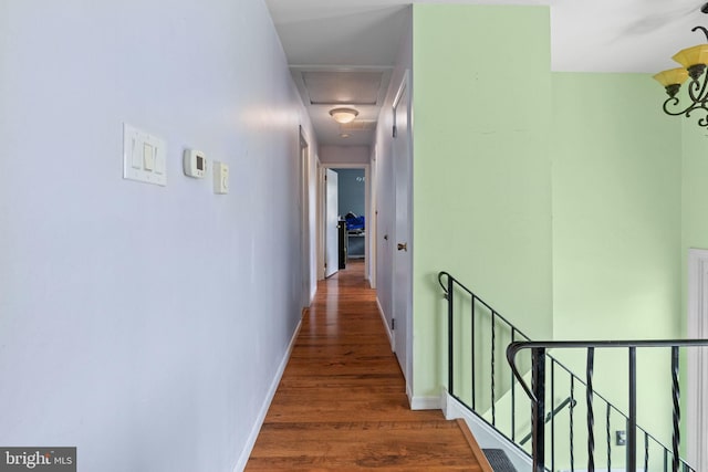 hallway featuring baseboards, wood finished floors, and an upstairs landing