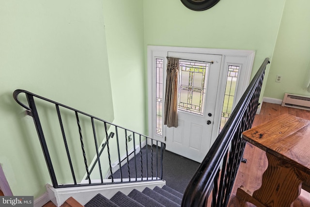 foyer entrance featuring baseboards, a baseboard heating unit, and stairway
