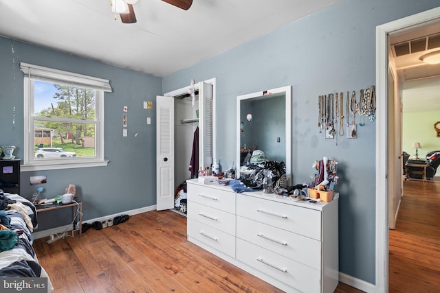 bedroom featuring a closet, baseboards, a ceiling fan, and wood finished floors