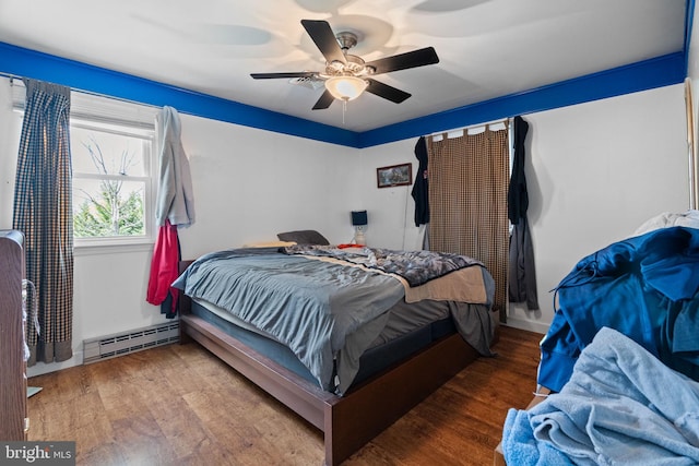 bedroom with ceiling fan, wood finished floors, and baseboard heating