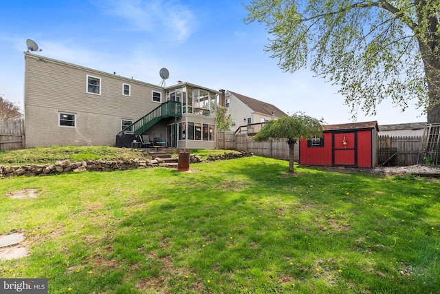 back of house featuring a storage shed, an outdoor structure, a fenced backyard, a yard, and stairs