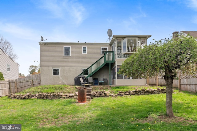 back of house featuring fence, a yard, stairs, and a sunroom