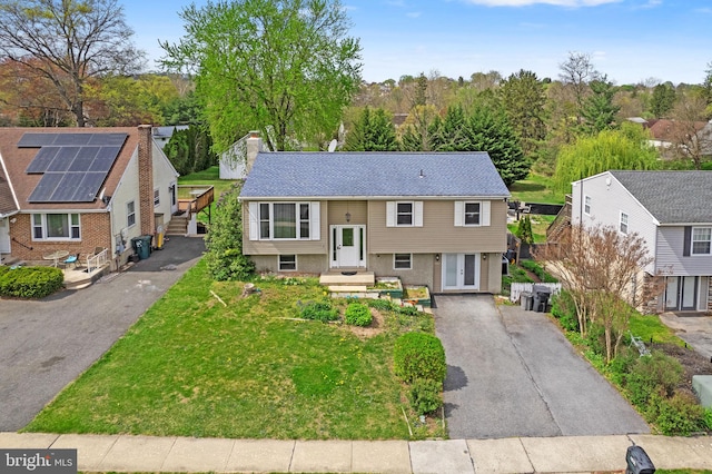 raised ranch with a residential view, a front lawn, and aphalt driveway