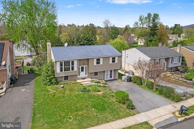 split foyer home featuring a residential view, a chimney, and aphalt driveway