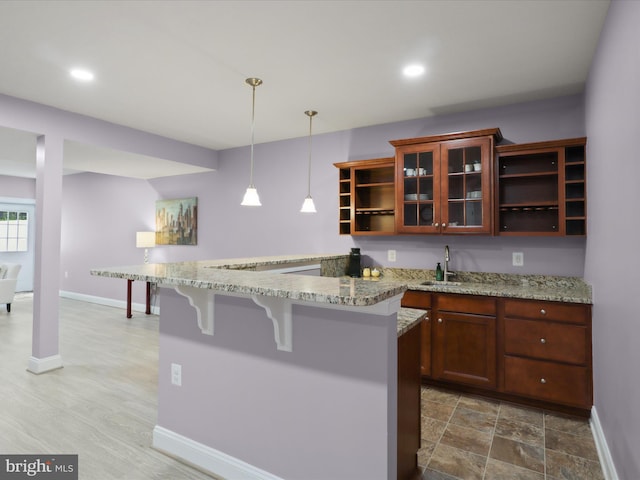 41909 Paddock Gate Pl, Ashburn, VA 20148 - kitchen featuring open shelves, a breakfast bar, a peninsula, baseboards, and hanging light fixtures