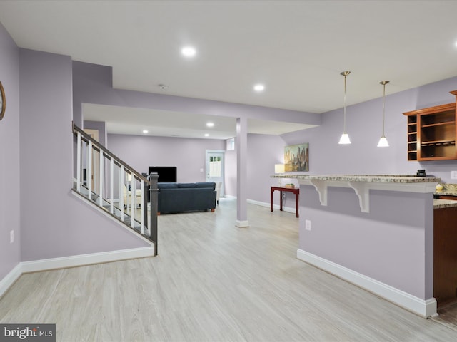 41909 Paddock Gate Pl, Ashburn, VA 20148 - kitchen featuring open shelves, light wood finished floors, a breakfast bar area, light stone countertops, and hanging light fixtures
