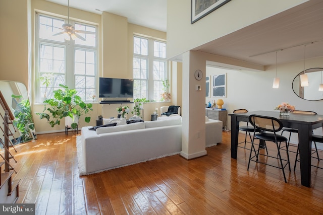 living area featuring track lighting, a ceiling fan, baseboards, and hardwood / wood-style floors