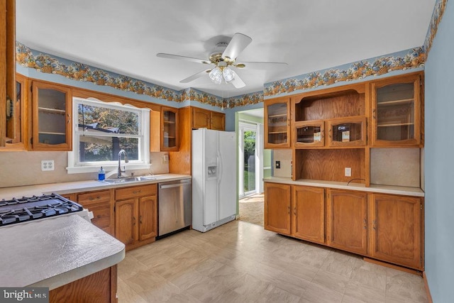 kitchen featuring ceiling fan, brown cabinets, dishwasher, a sink, and white fridge with ice dispenser
