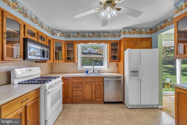 kitchen with a sink, light countertops, stainless steel appliances, and brown cabinets