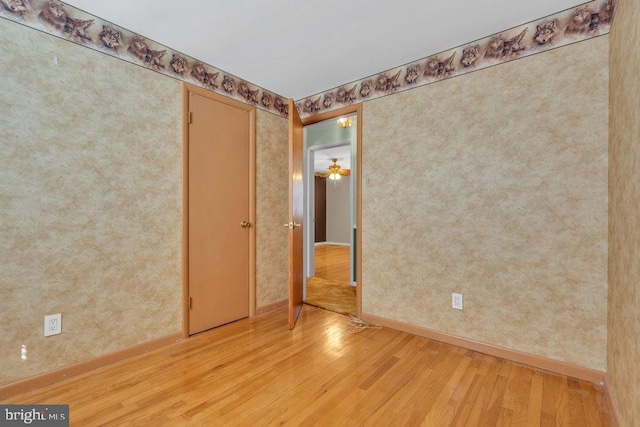 unfurnished room with baseboards, wallpapered walls, and light wood-style flooring