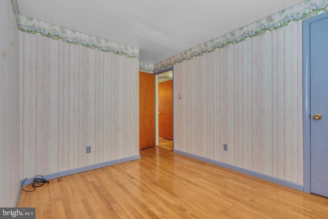 unfurnished room with baseboards, wood finished floors, and wallpapered walls