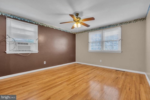 spare room with a ceiling fan, baseboards, visible vents, and wood finished floors