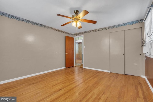 unfurnished bedroom featuring a closet, light wood-style floors, baseboards, multiple windows, and a ceiling fan